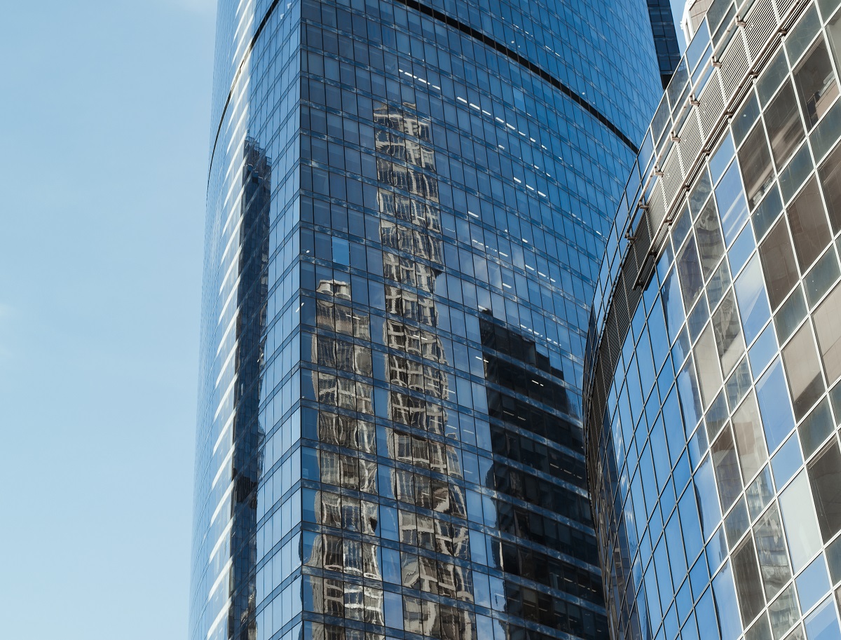 Skyscraper against the blue sky, exterior. Modern high-rise office building. Reflection of a skyscraper in the blue windows of a building
